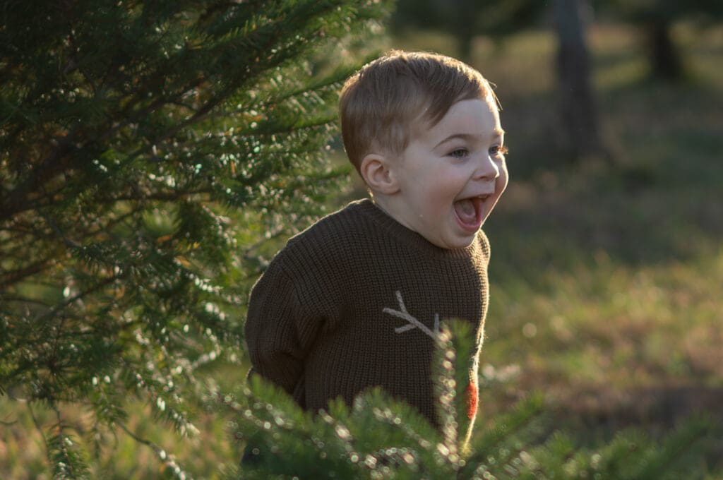 A boy smiles big at a a Christmas tree farm in Sussex County NJ