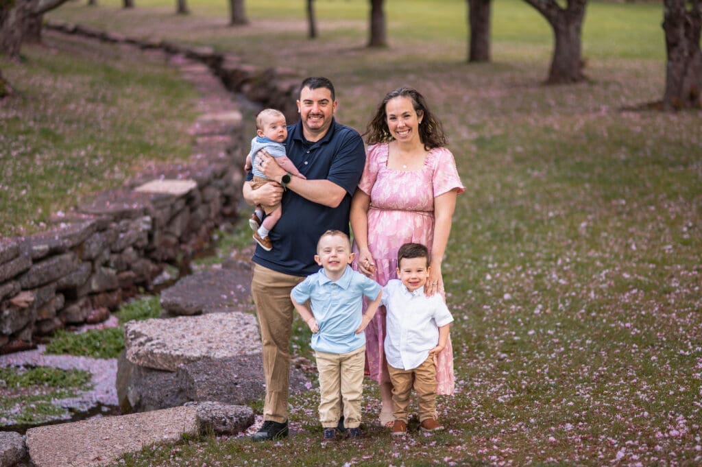A family of five is posing in a park.
